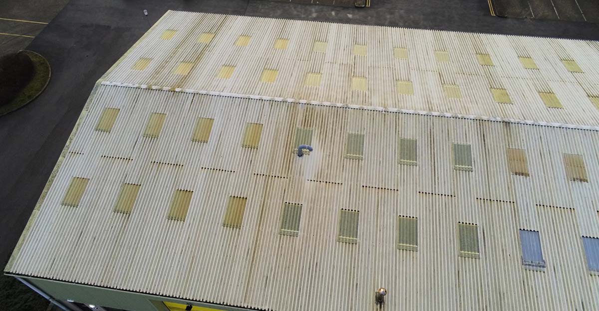 Aerial view of a building featuring a man standing on the roof, surrounded by a clear blue sky.