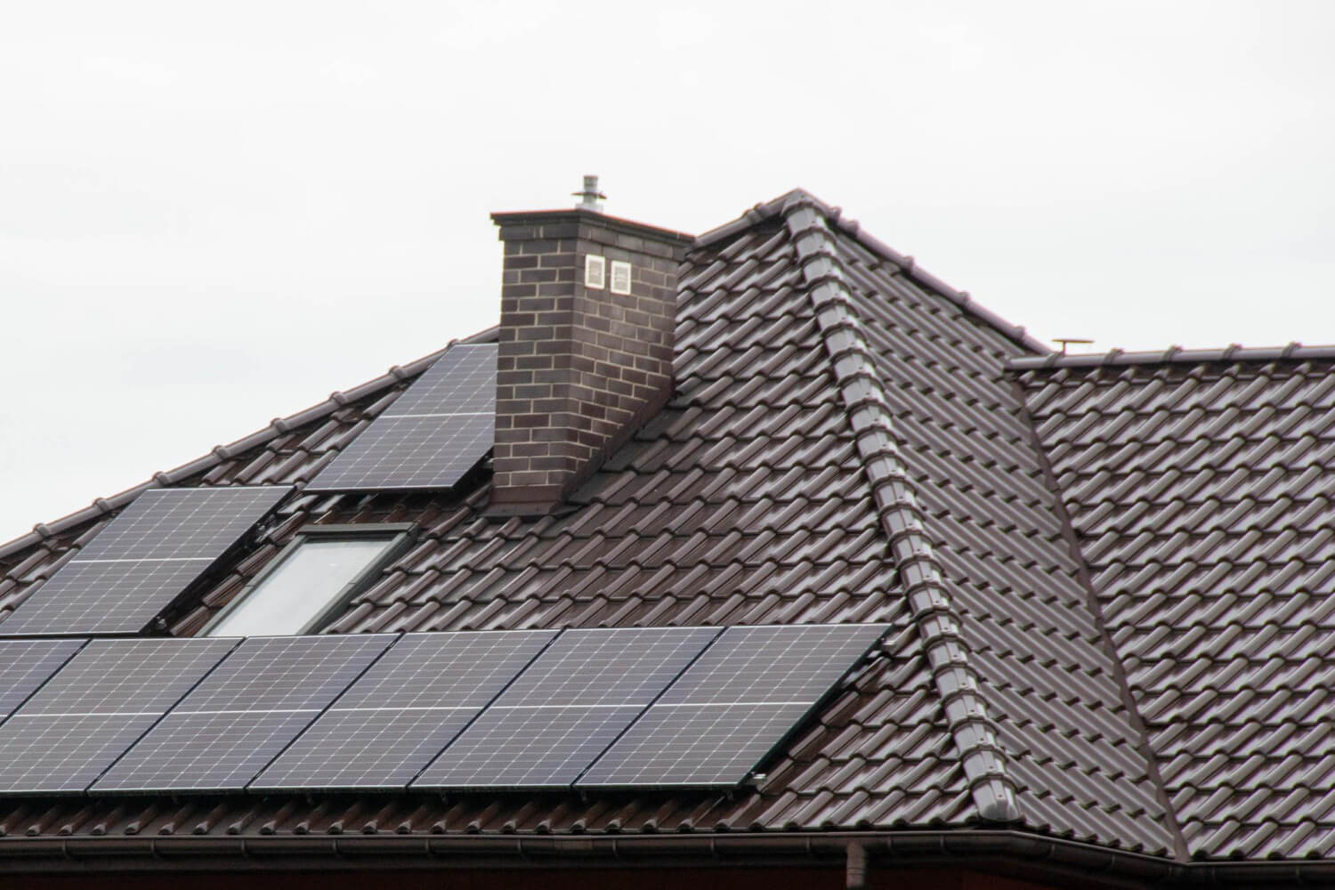A solar panel on a roof with the roof of a house