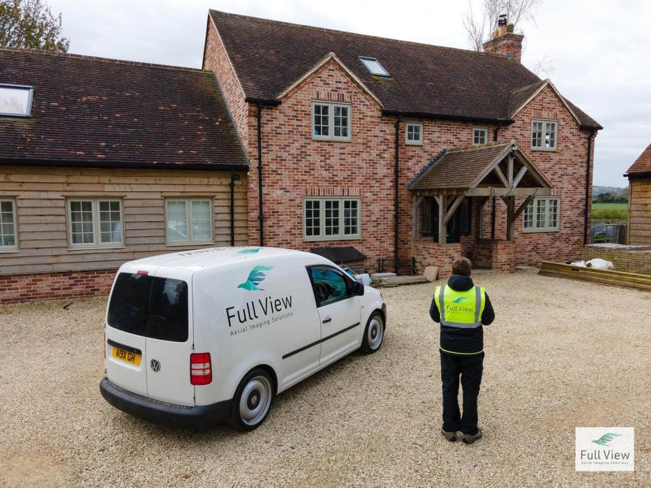 A man stands next to a van, with a house visible in the background